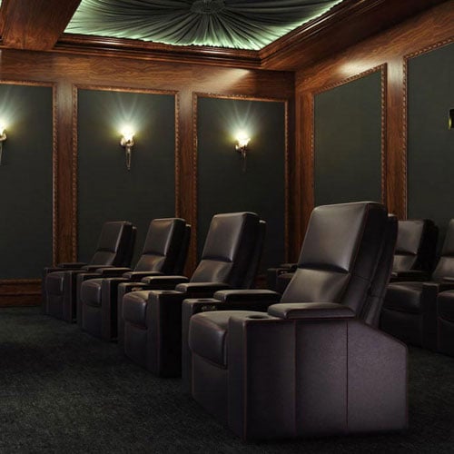 home cinema seating in black in room with wooden panelling on walls and sconce lights