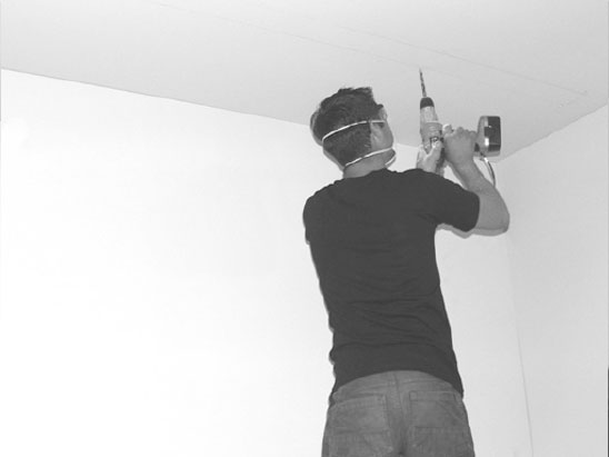 man drilling holes to fit projector screen