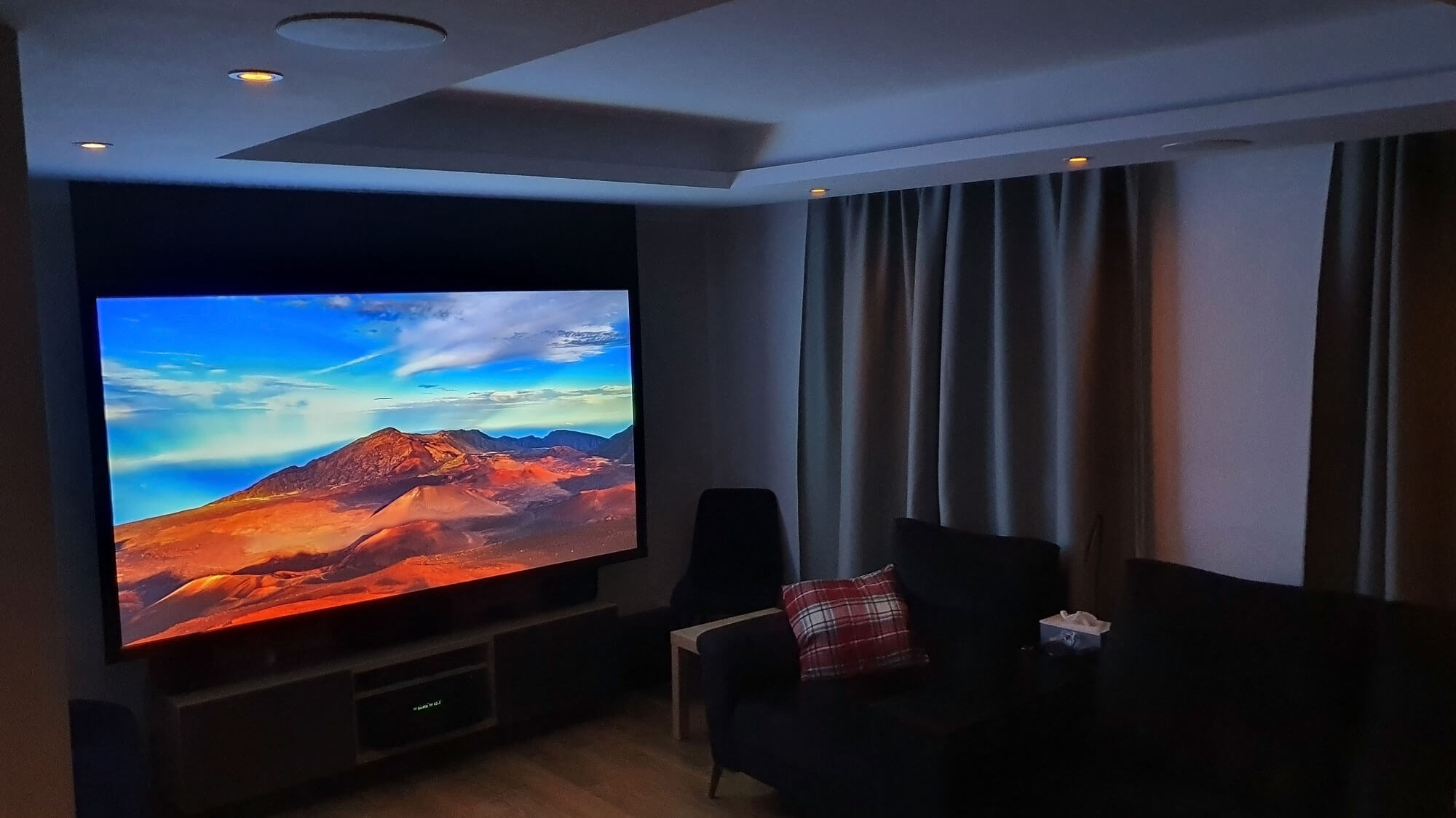 Dark living room with projector screen showing mountain scene